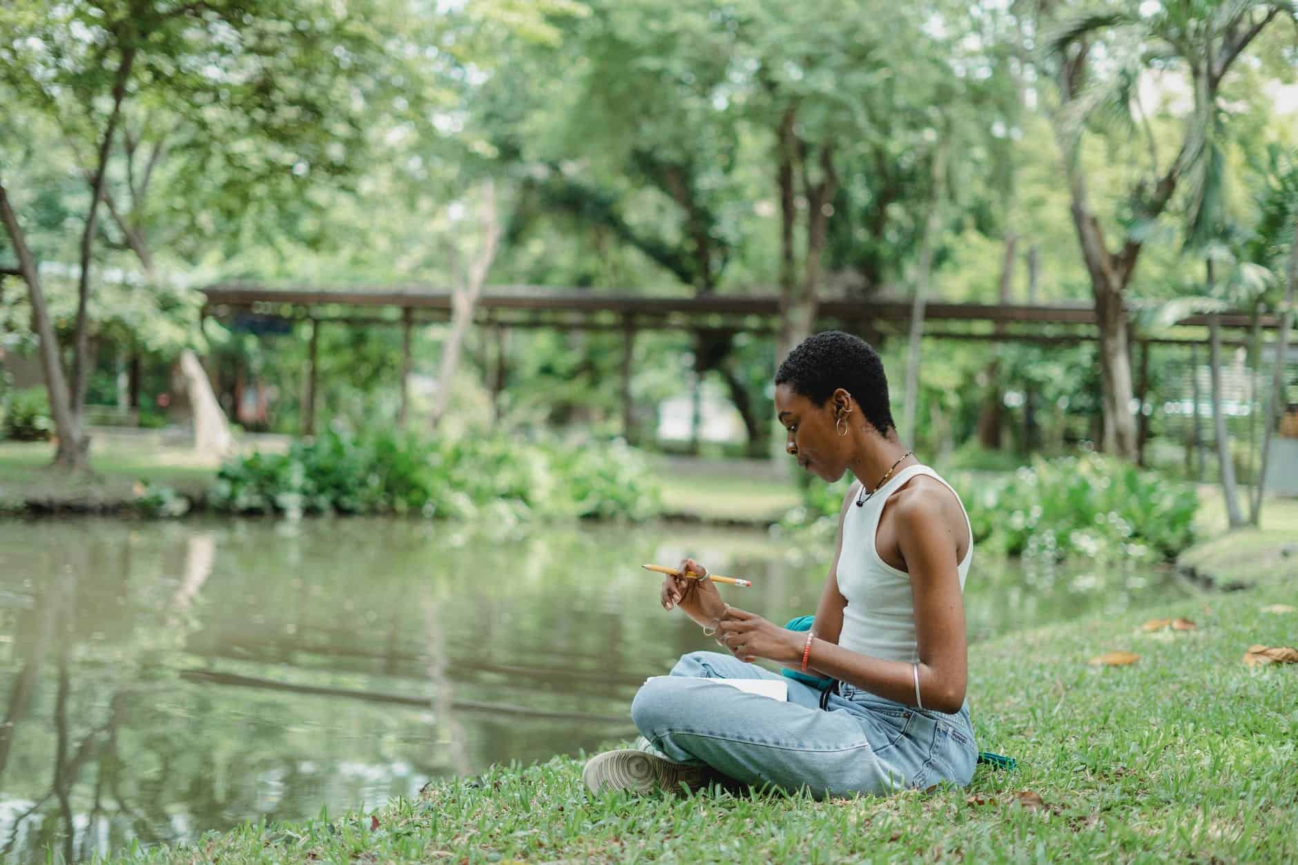 black woman sitting on grass with notebook